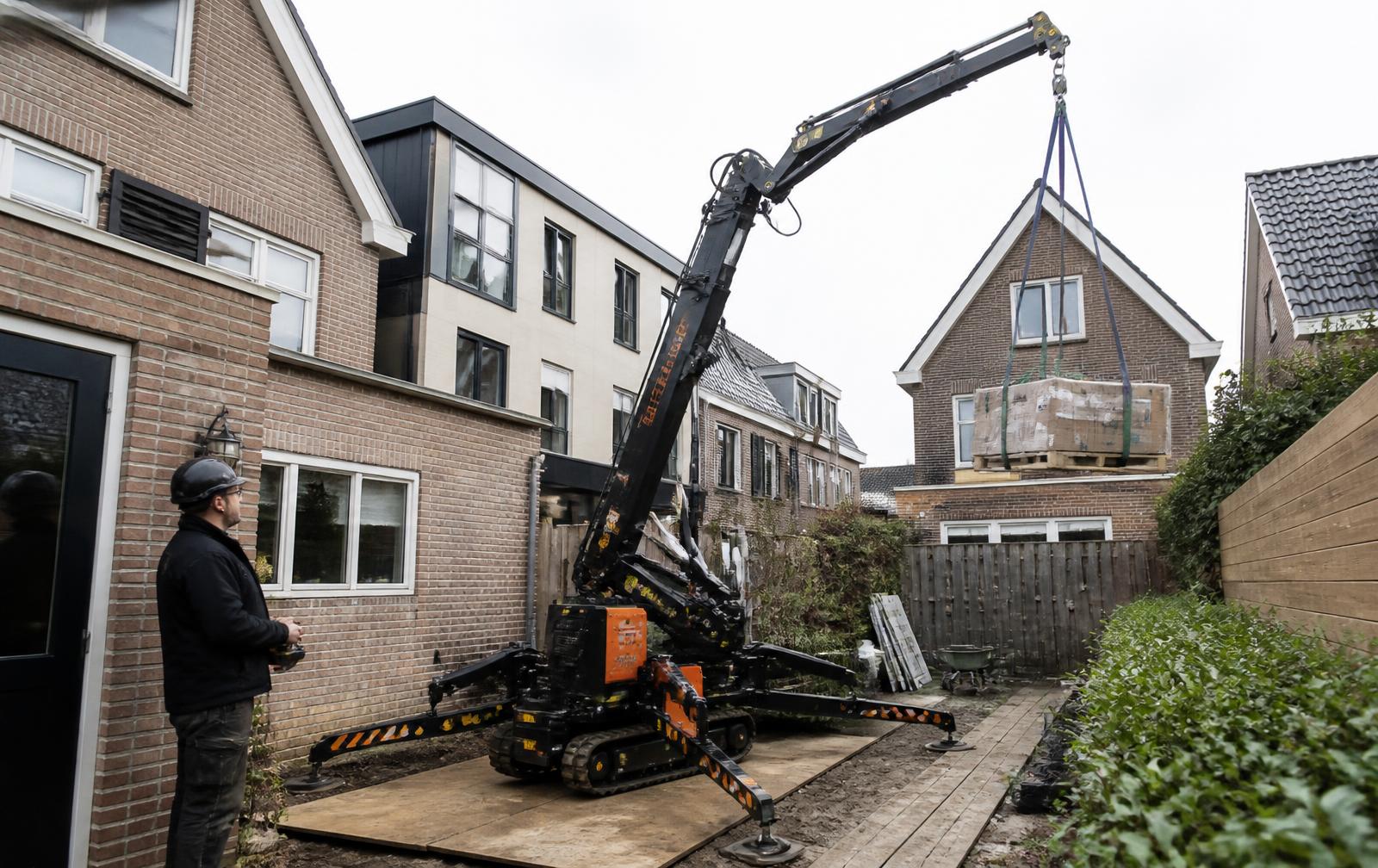 Compactkraan met machinist tijdens hijswerk op een moeilijk bereikbare locatie